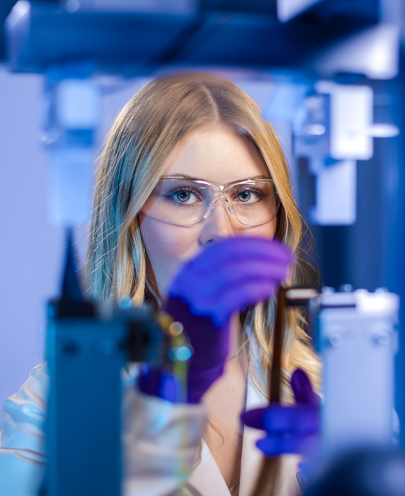 Person wearing safety goggles handling equipment in lab