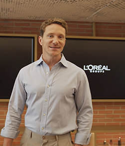 Person standing in office with L’Oréal logo screens behind