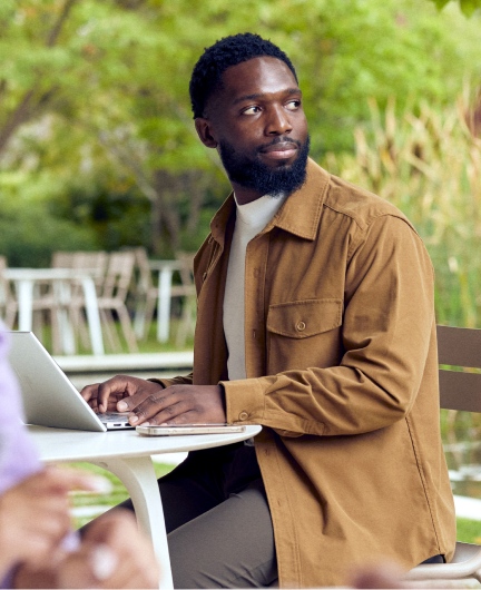 Person using laptop outdoors at café table workspace