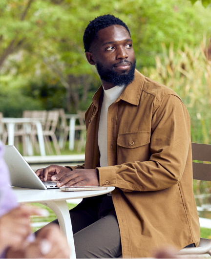 Person using laptop outdoors at café table workspace