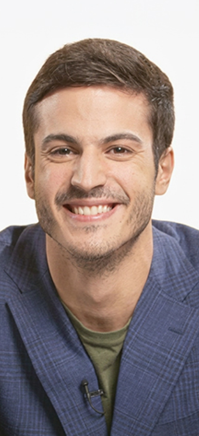 Close-up portrait of person smiling at desk with laptop