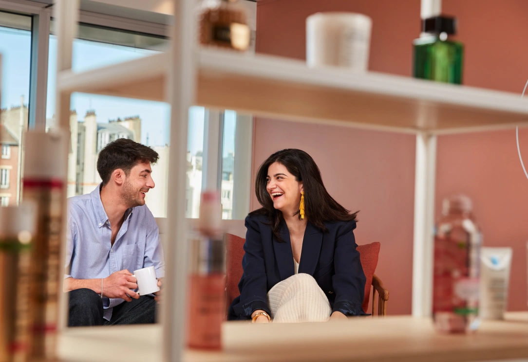 Two coworkers chatting and laughing in modern office lounge