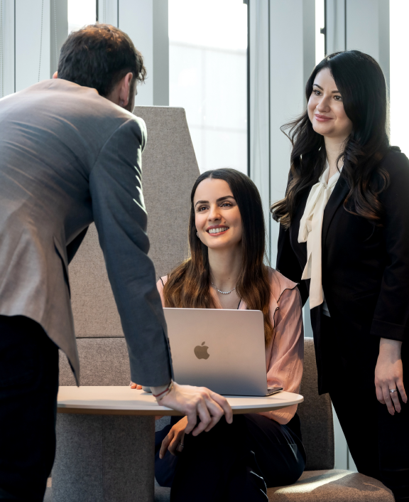 Three colleagues collaborating around a laptop