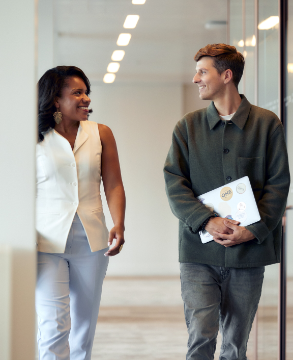 Two people walking and talking in office hallway