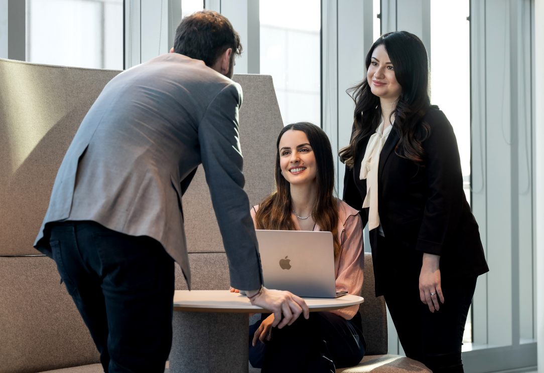 Three colleagues collaborating with laptop in office