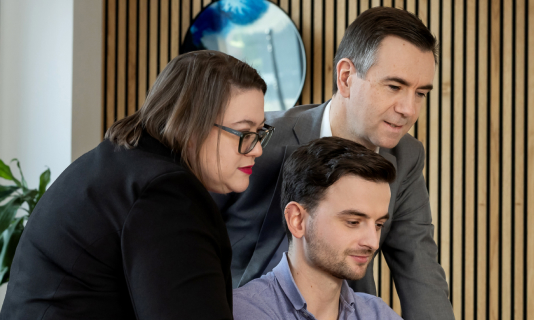 Three colleagues reviewing content on tablet together