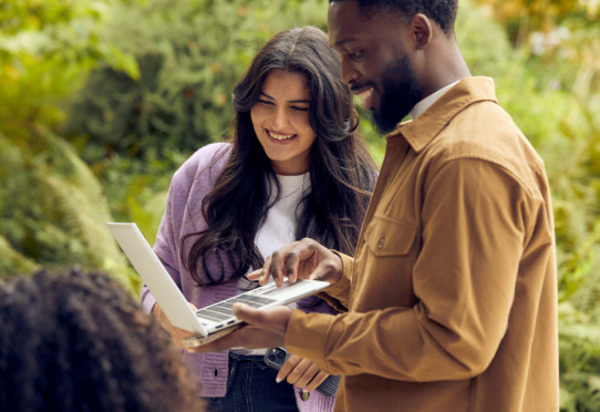 Two people using a laptop outdoors together