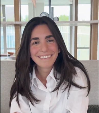 Person smiling while sitting indoors near a window