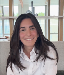 Personne souriante assise en intérieur près d’une fenêtre.