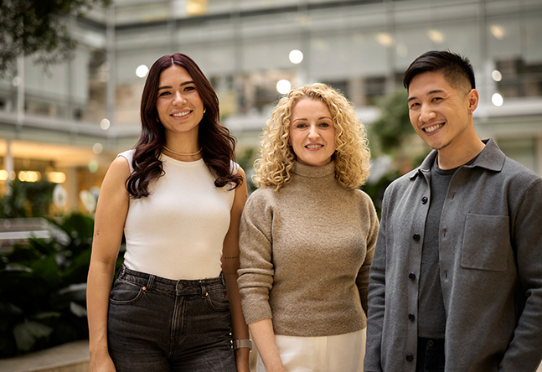 Three coworkers standing together in office space
