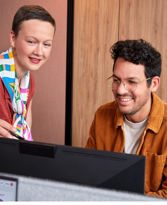 Two colleagues reviewing work on desktop