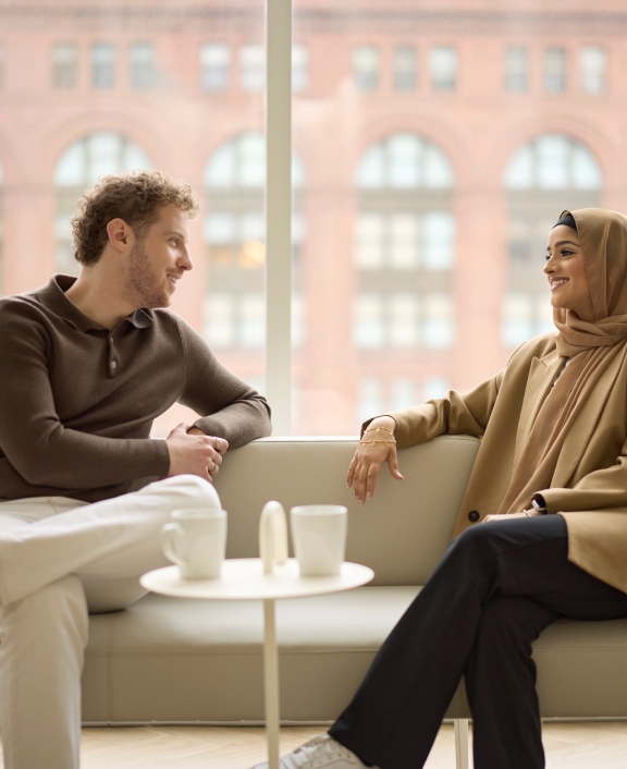 Two people chatting by window with coffee