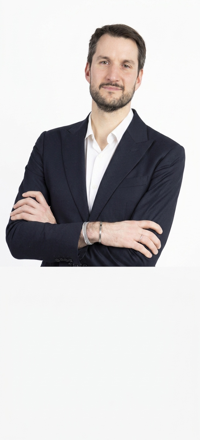 Person in suit standing with arms crossed indoors
