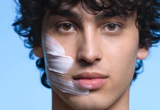 Person in profile with gloved hand touching chin .