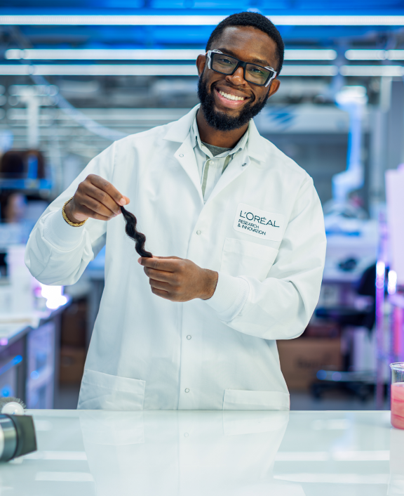 Lab worker holding hair strand in research lab