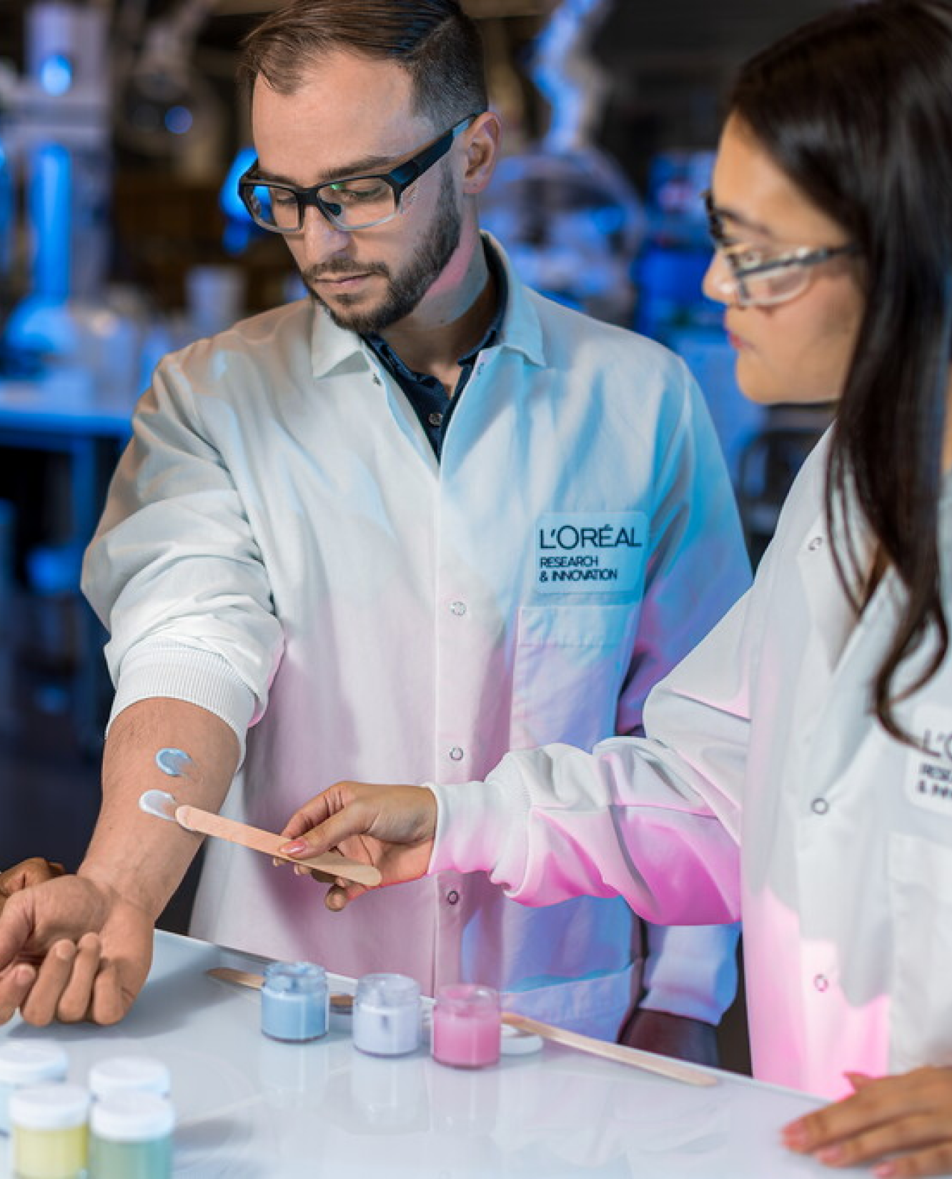 Two lab workers applying cream sample on arm