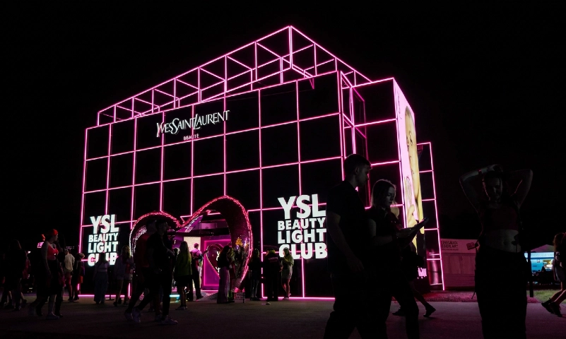 Pink neon YSL Beauty venue at night with crowds outside