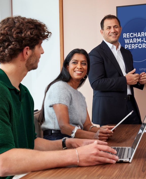 Two professionals presenting beside screen with slogan and tablet