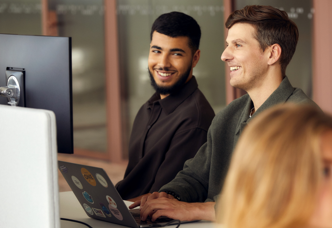 Two colleagues working at computers in modern office smiling