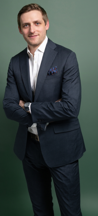 Professional portrait of person in suit with folded arms