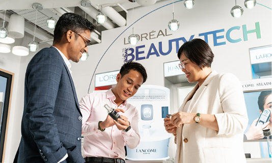 Three professionals interacting with beauty tech product display