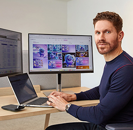 Person working at desk with dual monitors displaying design content