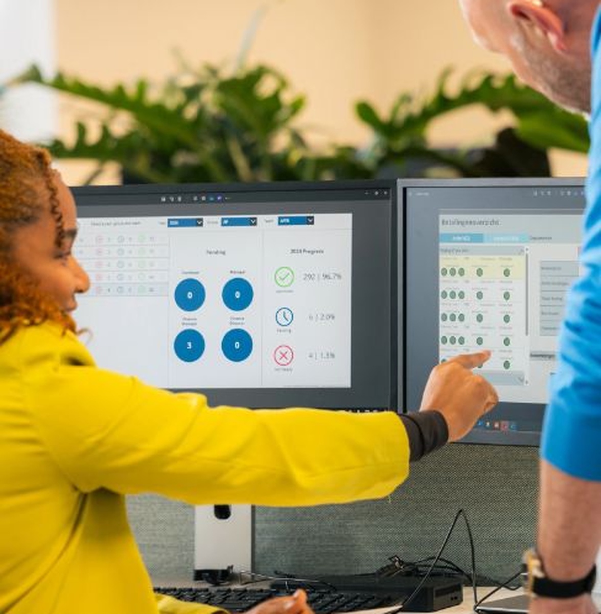 Twee mensen wijzen naar data op twee schermen