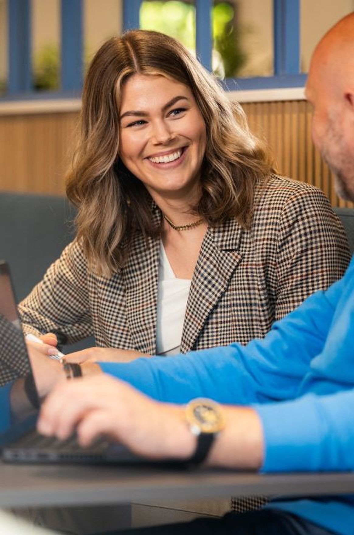 Persoon glimlacht terwijl hij werk bespreekt op een laptop