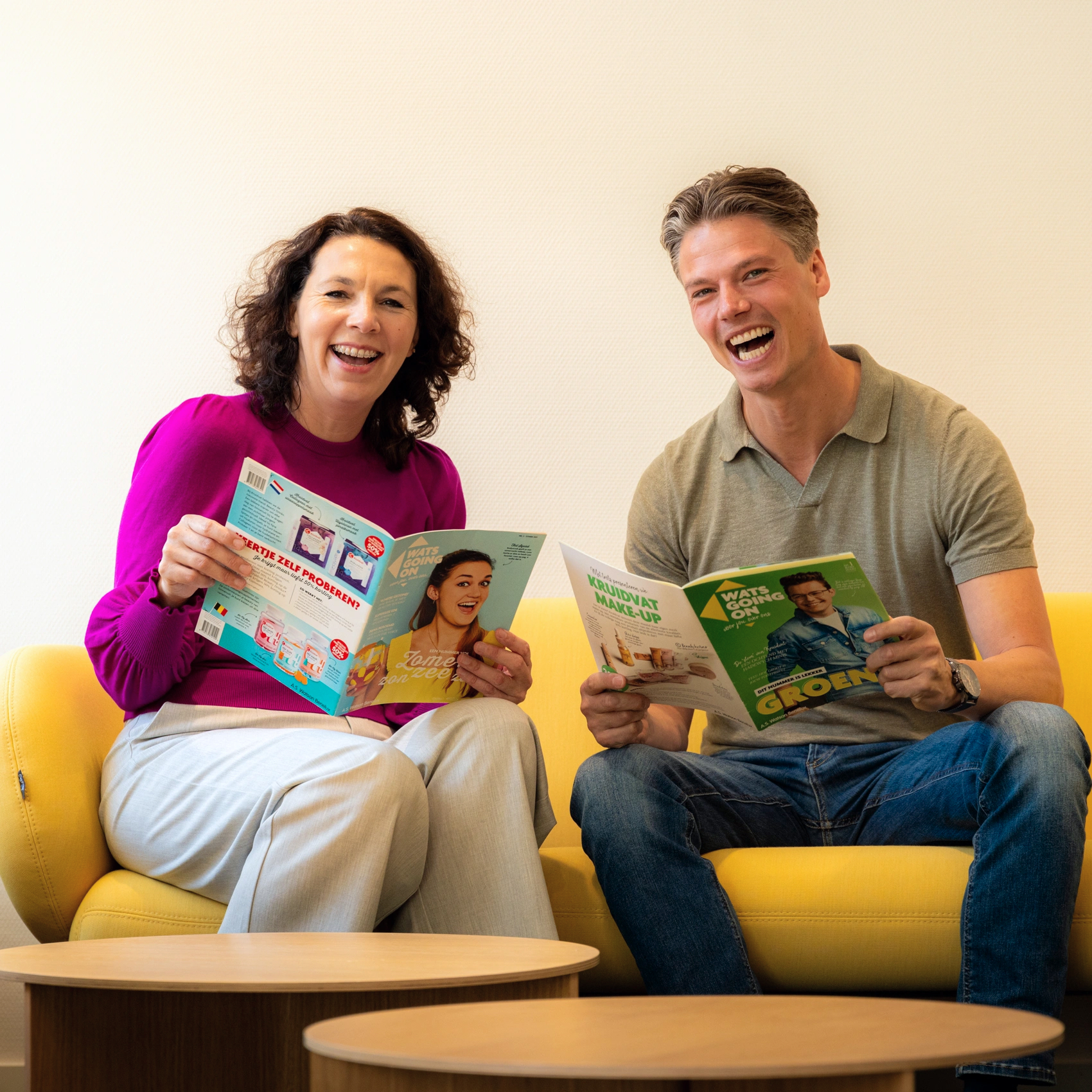 Twee mensen lezen magazines lachend