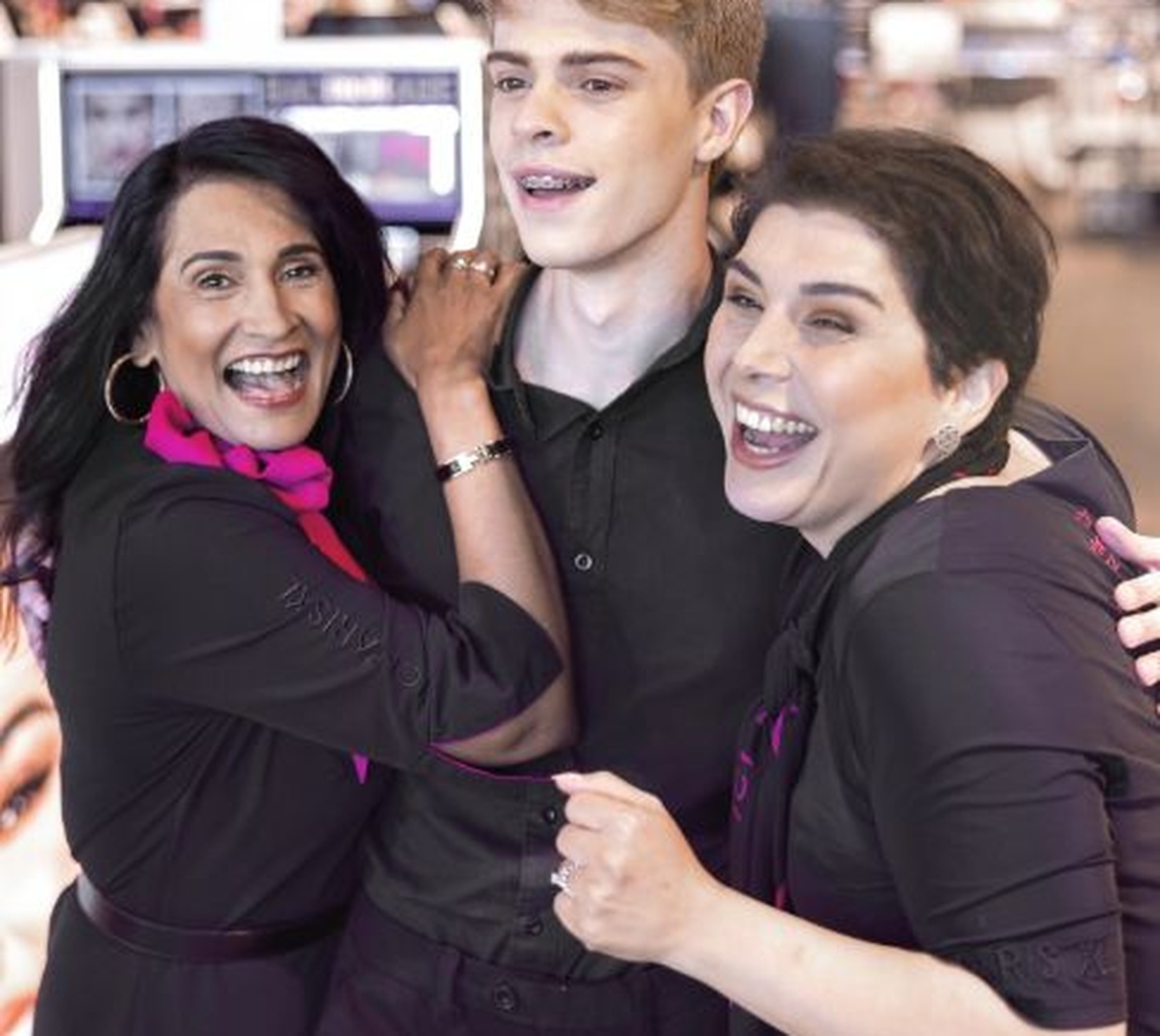 Drie personen in winkel omhelzen en lachen samen