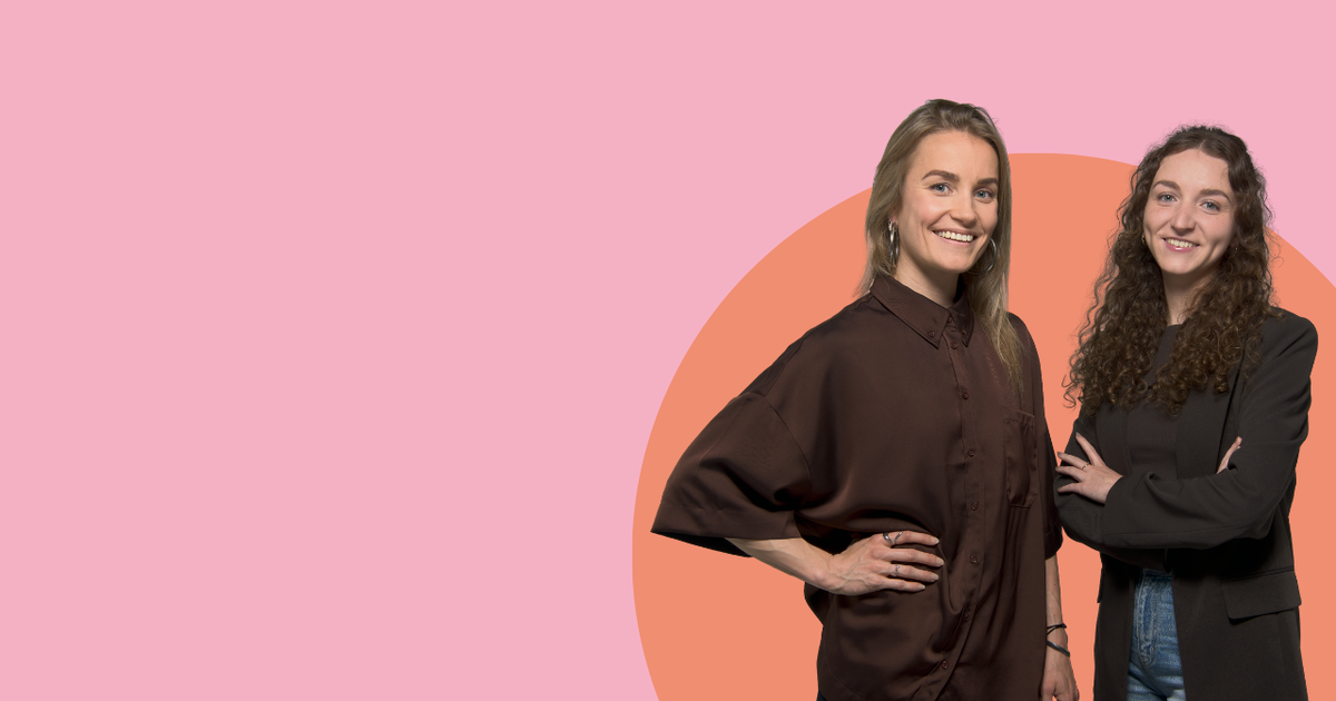 Twee personen poseren samen voor een roze achtergrond.