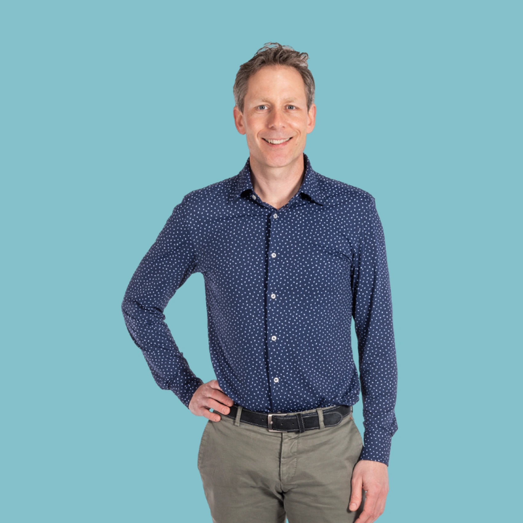 Persoon in blauwe stippenblouse staat lachend