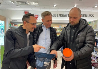 Drie personen bekijken product in winkel