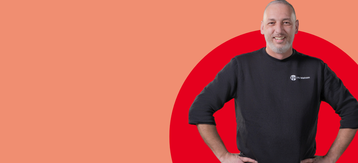 Medewerker in AS Watson-kleding poseert tegen een grafische achtergrond.