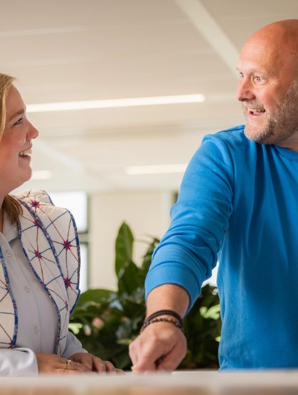 Twee mensen praten en lachen in een kantoorruimte