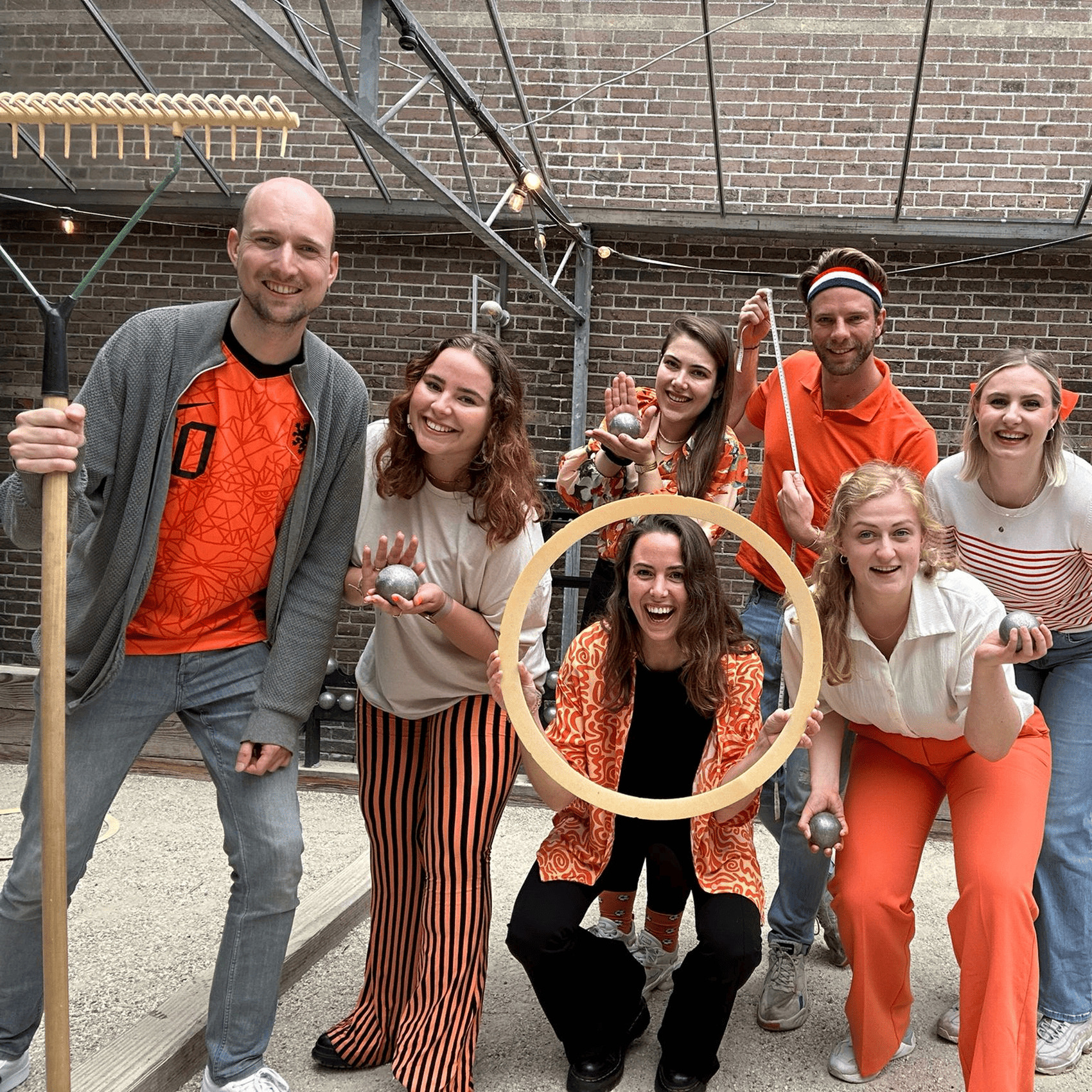 Groep speelt jeu de boules in oranje outfits