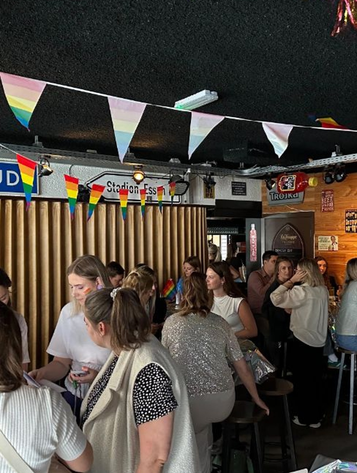 Drukke bar met mensen en regenboogvlaggen