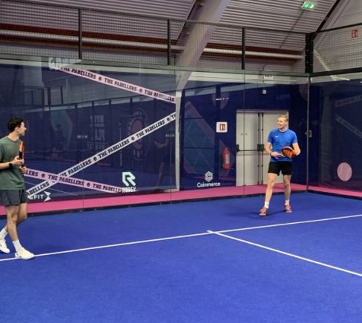 Twee spelers op indoor padelbaan met rackets