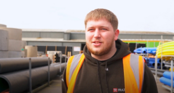 Person in safety vest at industrial pipe yard