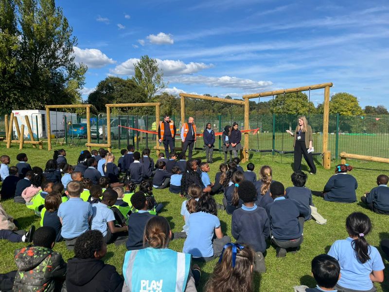 Children gather for playground opening event outdoors.