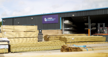 Lumber stacks outside industrial warehouse building