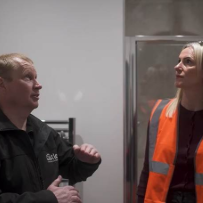Two people discuss work beside glass partition