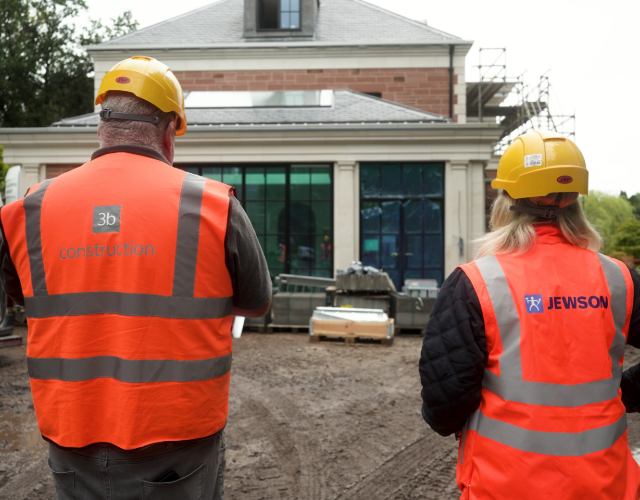 Workers in hi-vis vests inspect house build site
