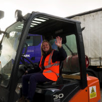 Person in forklift waving while wearing hi-vis vest