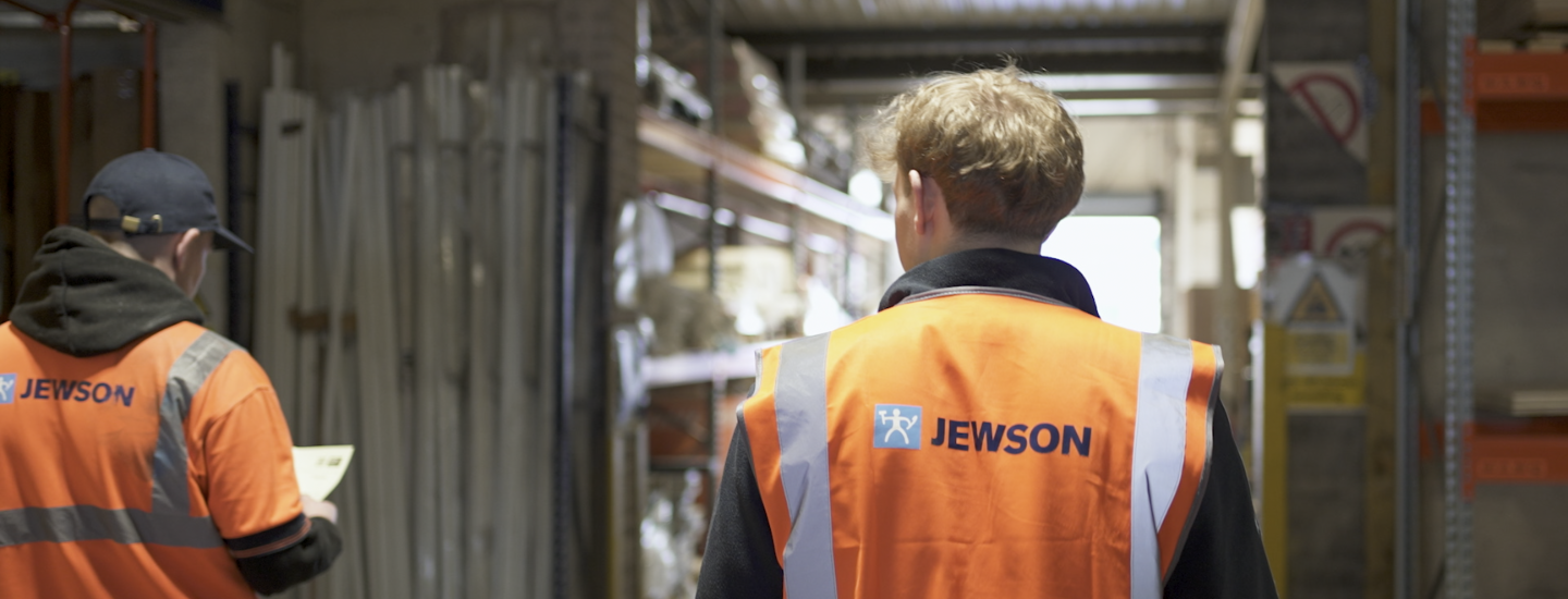 Workers in orange vests walking through warehouse