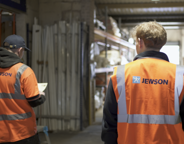 Workers in orange vests walking through warehouse