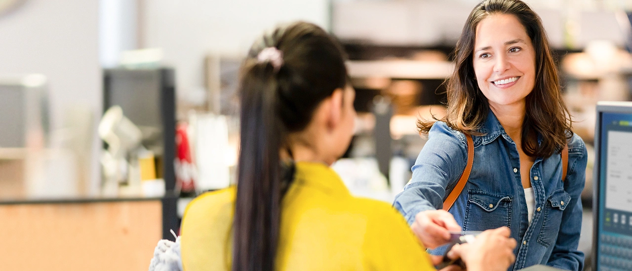 Persoon betaalt en geeft kaart aan medewerker shop