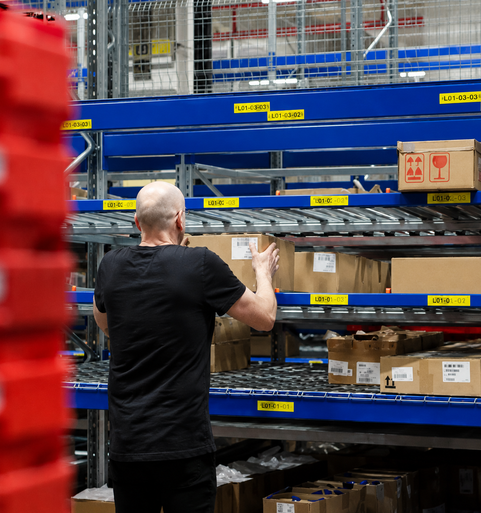 Medewerker plaatst doos in magazijnstelling