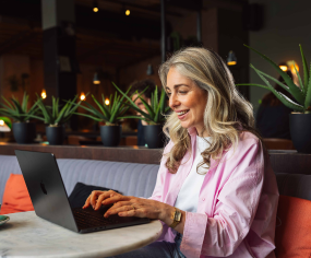 Persoon werkt op laptop aan tafel in een caf&eacute;