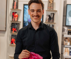Persoon toont roze product in moderne winkelruimte
